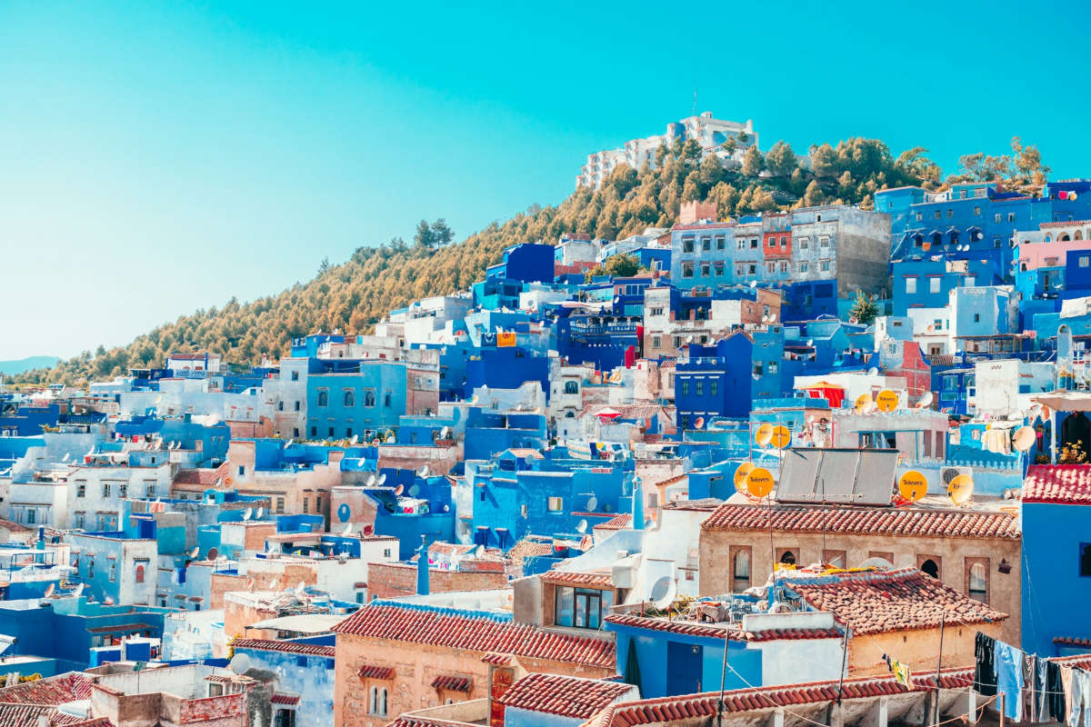 blue and white colored city buildings standing on a mountain slope 