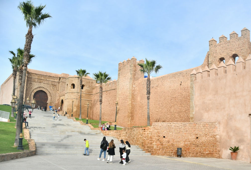 people taking pictures in front of the high walls of an old castle 